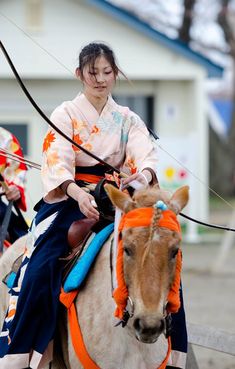 two women riding on the backs of horses in traditional japanese garb and headdress