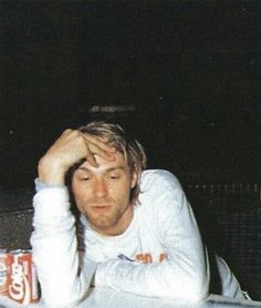 a man laying on top of a white table next to a can of coca - cola