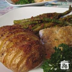 a white plate topped with potatoes and meat next to asparagus on a table