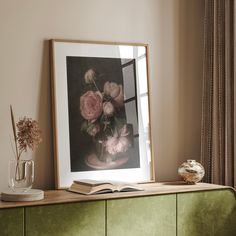 an open book is sitting on a dresser next to a vase with flowers in it