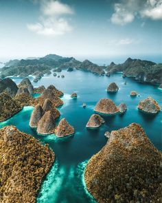 an aerial view of the ocean with many small rocks in the water and land around it