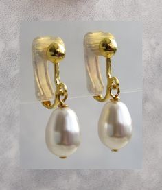 These understated elegant 9x14mm Swarovski white crystal pearl crystal  gold plated clip on earrings. The earrings is approximately 2.5cm long Available in  Silver plated, https://www.etsy.com/uk/listing/1468500517 Rose gold plated- https://www.etsy.com/uk/listing/1468502267 Will be sent in an organza gift bag  The colour of the actual earrings might be slightly different to the photo due to the lighting All measurement mentioned in this listing is approximate . More Clip on earrings available Classic Pearl Drop Clip-on Earrings, Formal White Pearl Drop Clip-on Earrings, Gold Pearl Charm Clip-on Earrings, Gold Clip-on Pearl Earrings, Gold Clip-on Pearl Earrings With Pearl Charm, Gold Clip-on Earrings With Pearl Charm, Formal Dangle Pearl Clip-on Earrings, Classic Pearl Drop Dangle Clip-on Earrings, Gold Teardrop Pearl Drop Clip-on Earrings