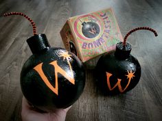 two black vases with orange designs on them sitting on a wooden floor next to a box