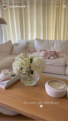 a living room with white furniture and flowers on the coffee table in front of it