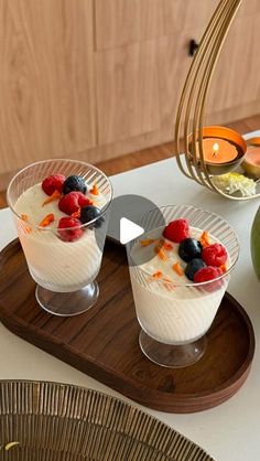 two desserts on a wooden tray with fruit and candles in the backround