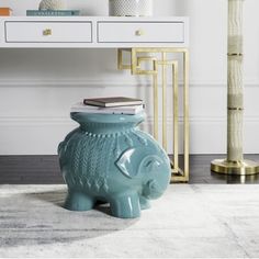 an elephant shaped vase sitting on top of a rug in front of a white table