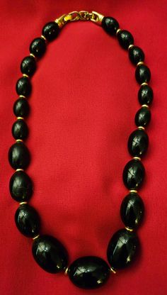 This is a beautiful Vintage beaded Necklace by D'Orlan. It has black beads that are oval shaped, with 3 different sizes and gold spacers between each bead. The back clasp is a double clasp. It is stamped DORLAN. The gold spacers and the back clasp are plated by a high standard plating process. Measured while wearing, the drop is 7.5 inches. The total open length is about 18 inches. This is such a beautiful classic necklace. This is pre-loved. As is. Black Oval Beaded Necklaces, Black Beaded Jewelry With Oval Beads, Elegant Oval Gemstone Beads, Black Oval Gemstone Beads Jewelry, Black Beaded Necklace With Large Beads For Formal Occasions, Black Necklace With Oval Spacer Beads, Oval Black Beads For Jewelry Making, Black Jewelry With Faceted Oval Beads, Black Jewelry With Oval Faceted Beads