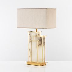 a lamp that is sitting on top of a white table with a beige shade over it