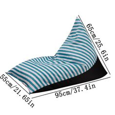 a blue and white striped pillow sitting on top of a black floor next to a ruler