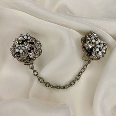 "A very nice pair of sweater clips from repurposed vintage unsigned clear rhinestone and milk glass bead costume earrings, found with one broken clip.   These repurposed flower cluster has clear rhinestones scattered on a silver tone filigree framework, accented with tiny wired milk glass bead flowers. Each earring is about 1.25\" across Settings and chains are gold or silver tone base metal, all from pre-owned vintage elements.   Chains are 3.5-4\"long. Clips are new; they are  cushioned and safe for most fabrics. if you have a pair of old screw back or clip on earrings, I can make them into sweater clips.  Write for information." Sweater Clips, Bead Flowers, Collar Clips, Sweater Clip, Flower Cluster, Vintage Elements, Costume Earrings, Repurposed Vintage, Shoe Clips