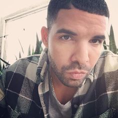 a close up of a person wearing a plaid shirt and looking at the camera with a serious look on his face