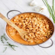 a pot filled with macaroni and cheese next to garlic