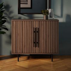 a wooden cabinet sitting on top of a hard wood floor next to a potted plant