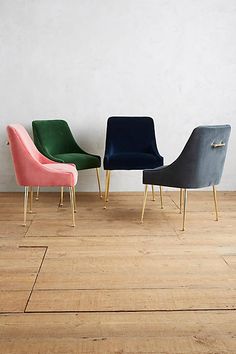 three chairs sitting next to each other on top of a hard wood floor in front of a white wall