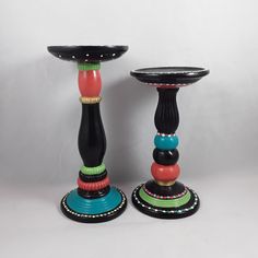 two colorful candlesticks sitting next to each other on top of a white surface