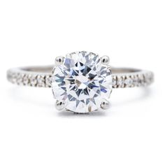 a diamond engagement ring with diamonds on the band and an oval center stone in white gold