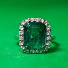 an emerald and diamond ring on a green surface