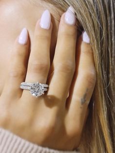 a close up of a woman's hand with a diamond ring on her finger