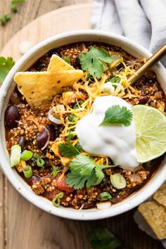 a white bowl filled with chili, beans and tortilla chips