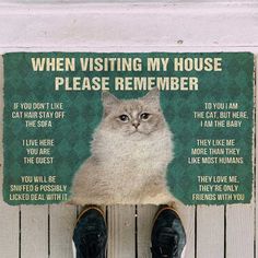 a cat sitting on top of a wooden floor next to a sign that says, when visiting my house please remember