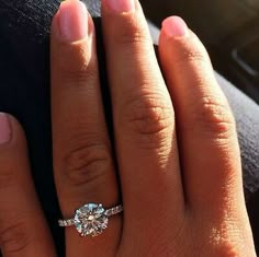 a woman's hand with a diamond ring on top of her finger and the other hand