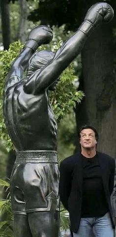 a man standing next to a statue of a baseball player