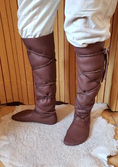 a person standing on top of a white rug wearing brown boots with ties around the ankles