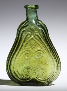 a green glass vase sitting on top of a table