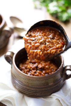 a spoon full of chili being lifted from a pot