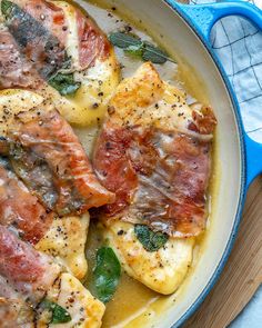 some meat and vegetables are cooking in a blue skillet on a wooden table top