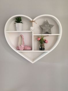 a white heart shaped shelf with shoes and flowers on it, in the shape of a heart