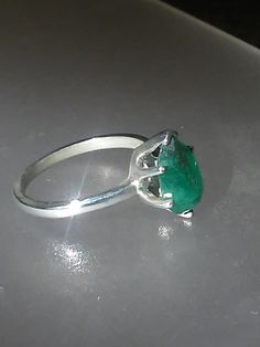 Imperfectly Perfect! This emerald came from a huge lot acquired in the late 70s. The natural inclusions in this stone along with the faceting on the back of the emerald make this ring so unique. This natural 1.56ct emerald is pear shaped cut and pavilion set (back of the stone is set face up). There is a natural clarity characteristic towards the lower tip of pear. Sterling silver mounting has five prongs and a v tip to protect the point of pear. High polished finish band tapers from 1.7 to 1.5 Elegant Untreated Oval Emerald Ring, Faceted Emerald Ring Fine Jewelry, Emerald Cut Emerald Gemstone In Prong Setting, Emerald Cut Emerald Gemstones With Prong Setting, Fine Jewelry Faceted Emerald Ring, Oval Emerald Ring With Prong Setting, Elegant Untreated Green Emerald Ring, Elegant Untreated Emerald Ring For Anniversary, Oval Emerald Gemstones With Prong Setting