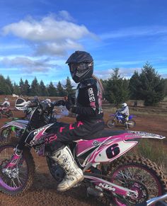 a person on a dirt bike with other people in the background and trees behind them