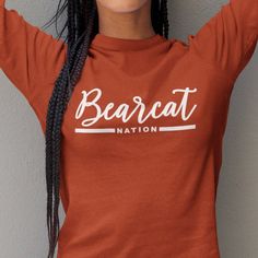 a woman wearing a bearcat nation t - shirt with braids on her hair