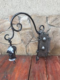 two metal hooks on the side of a wooden table next to a stone wall and wood floor