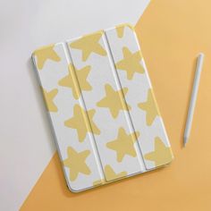 a yellow and white star patterned ipad case next to a pencil on an orange background