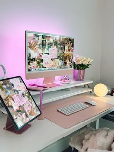 a desk with a computer monitor, keyboard and mouse next to a pink flower vase