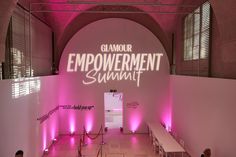 the entrance to glamour emporishment summit is lit up with pink lights and white benches