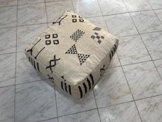 a white and black ottoman sitting on top of a tiled floor