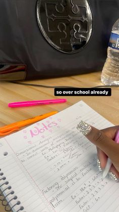 a person writing on a notebook next to a bottle of water and a bag with the words so over school already