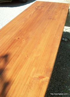 a wooden table sitting on top of gravel next to a parked truck in the background