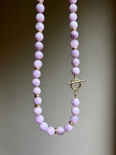 This classic kunzite necklace is made of top quality round beads and complimented with gold vermeil details. Kunzite's powers help alleviate stress and negative emotions that have the tendency to stay with us daily. Kunzite helps in reconnecting the heart with the mind and emotions, removing any blockages in-between the two. MATERIAL  Kunzite, gold vermeil (18k gold over sterling silver)  SPECIFICATIONS Length: 46 cm (18 inches) Handmade in Spain Necklace comes in a gift box Worldwide shipping w Elegant Toggle Necklace With Gemstone Beads For Gift, Gift Toggle Necklace With Single Strand Round Beads, Handmade Toggle Necklace With Round Beads As Gift, Beaded Toggle Necklace With Round Beads As Gift, Beaded Toggle Necklace With Round Beads, Kunzite Necklace, Kunzite Jewelry, Purple Stone Necklace, Pink Beaded Necklace