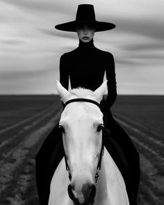 a black and white photo of a woman on a horse