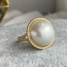 One piece of stunning statement piece made with large genuine mabe pearl and 14k solid gold * Center stone: Genuine White Mabe Pearl, 15-16mm in size * Ring measurement: 19.5mm wide, 1.2 to 1.6mm band thickness, 2.5mm bottom band width * Metal: 14K solid gold * Stamp: 14k ❤️Follow us on Instagram @ elekalonjewelry for latest projects and designs. *If you have any questions, please feel free to message us. Mabe Pearl Ring, Elegant Gold Moonstone Cabochon Ring, Luxury Yellow Gold Pearl Ring With Cabochon, Elegant Round Cabochon Pearl Ring, Heirloom High Luster Round Pearl Ring, Heirloom Pearl Ring With Cabochon, White Pearl Ring, Cultured Pearl Ring, June Birthstone Ring