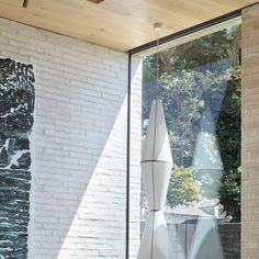 a white vase sitting on top of a table in front of a brick wall and window