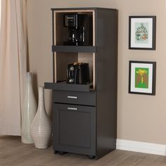 a small black cabinet in a living room next to a vase and pictures on the wall