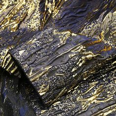 a blue and gold tie laying on top of a black tablecloth covered in metallic foil