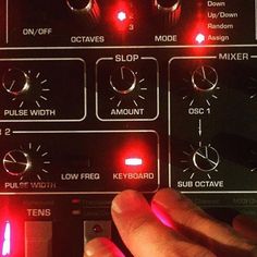 a hand is touching the knobs on a sound board with red light coming from it