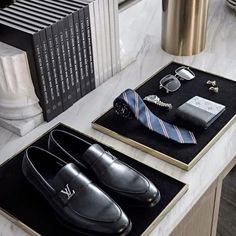 a pair of shoes and tie sitting on top of a table next to a book