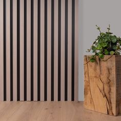 a wooden box with a plant in it sitting on the floor next to a striped wall